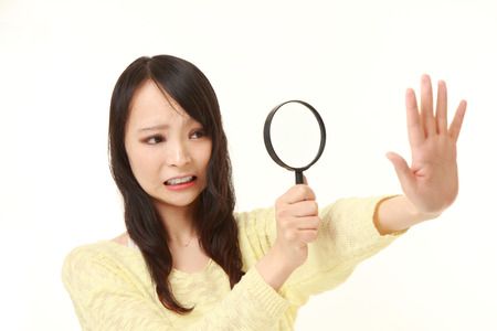 shocked young woman looking through a magnifying glass her nailsの写真素材