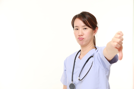 Japanese female doctor showing thumbs down gestureの写真素材