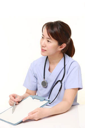 Japanese female doctor with clinical record talks to her patientの写真素材