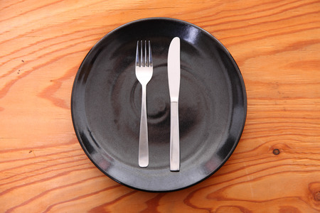 black dish on the wooden table with cutlery meaning FINISHED