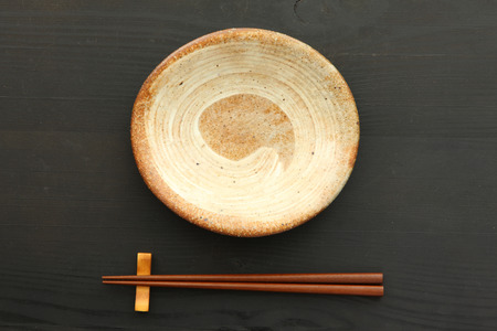 empty clay dish with chopsticks on the black table