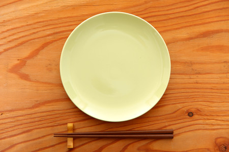 empty green dish on the wooden table with chopsticksの写真素材