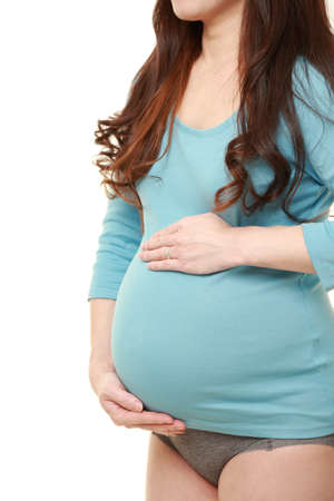pregnant woman touching her belly in studio shot on white backgroundの写真素材