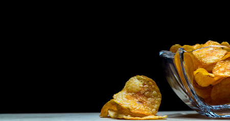 potato chips in a glas bowl on a wooden desk.