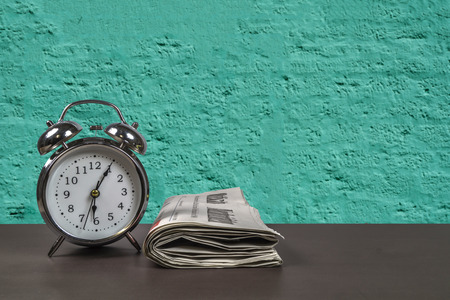 Retro alarm clock and newspaper on a desk.