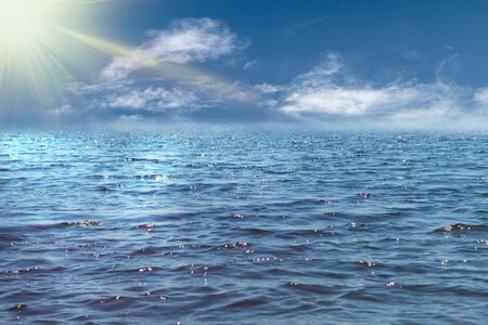 Beautiful blue sea ocean surface with ripples and blue sky with clouds and sun.の写真素材