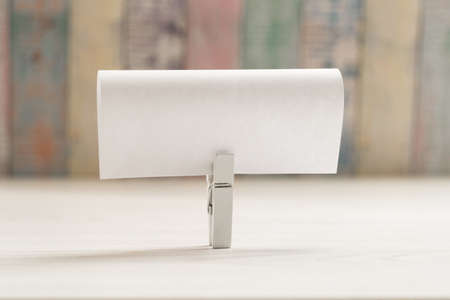White wooden cloth pin with a blank paper.
