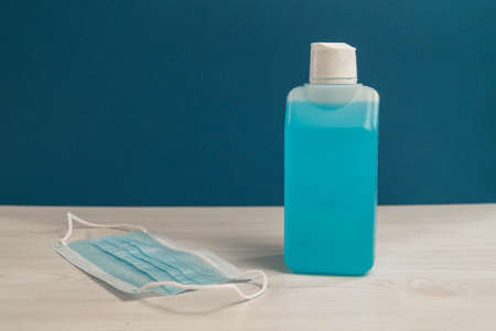 Unlabeled desinfection bottle and blue mask on a table.の写真素材
