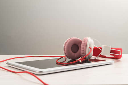 Headphones with white tablet notebook on a table.の写真素材