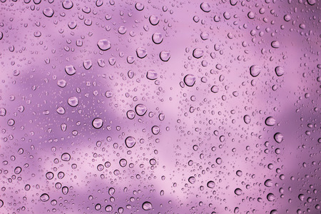 Water drops on glass background purple sky.