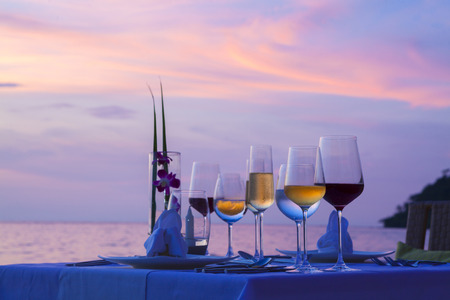 Silhouette glass of wine And equipment on a wooden table with seascape and skyline in the evening with sunset tone style.の写真素材
