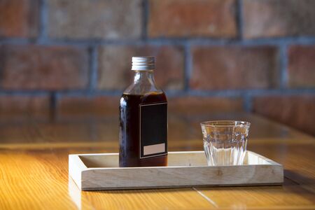a glass and coffee in a bottle ready for serve to customer,Brick wall background.
