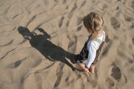child and his shadow in sandの写真素材