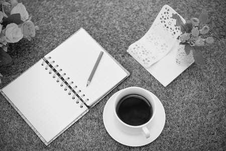 Dramattic moment .Have a cup of black coffee.Writing on copy space note book . with Pencil on grass Background.With selective focus.の写真素材