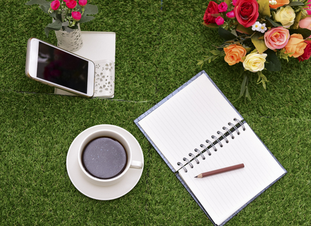 Have a cup of black coffee.Writing on copy space note book . with Pencil on green grass Background.With selective focus.の写真素材