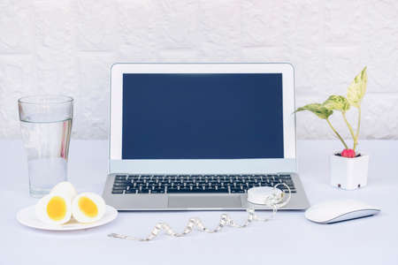 Glass of mineral water with boiled eggs and laptop computer isolated on white background. Dairy diet nutrition healthy eating.の写真素材