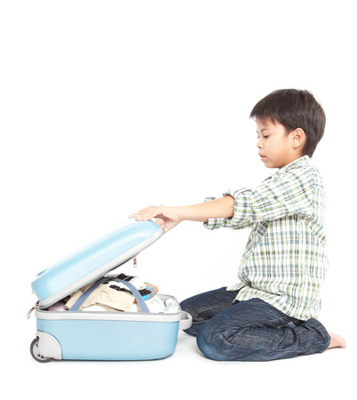 A little smiling boy with a suitcase is standing on the white backgroundの写真素材