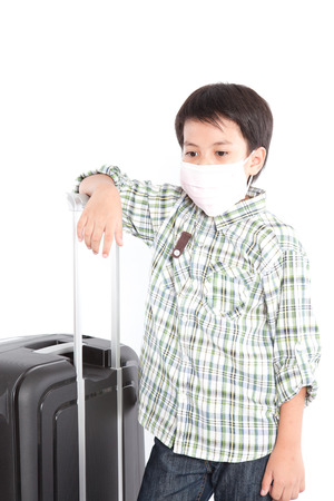 A little smiling boy with a suitcase is standing on the white backgroundの写真素材