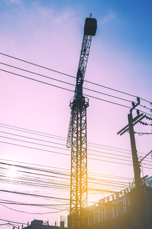 Silhouette construction site with crane. high voltage pole and blue sky background. image with sunset.の写真素材