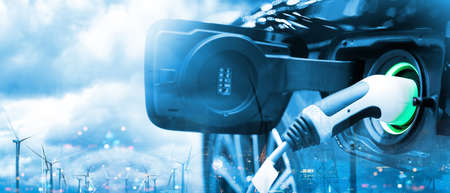 Charge EV car vehicle electric battery on station with wind turbine blue sky blur bokeh city on the panoramic background. Idea nature electric energy technology green eco concept. Double exposure.の写真素材
