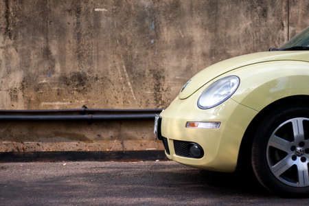 Modern yellow Volkswagen Beetle car parked near the old wall at February 16, 2014 in Bangkok, Thailandのeditorial素材