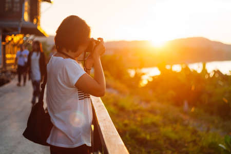 Young tourists are photographing the sunset with film camera, which is a flare of orange light beautifullyの写真素材