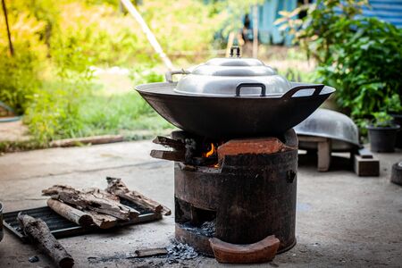 Aluminum steamer pot with big black pan on firewood burning stove for cooking thai dessertの写真素材
