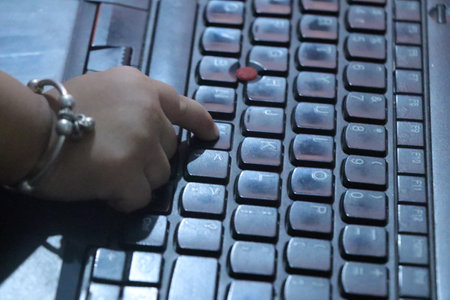 Close up of a male hand typing on a laptop computer keyboard.の写真素材