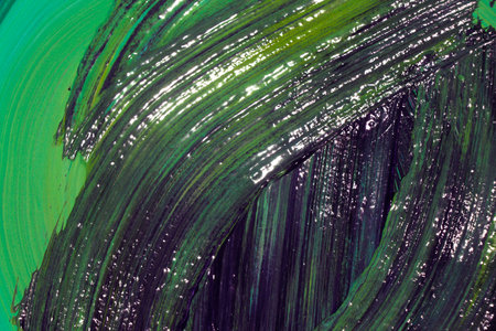 Green and black acrylic paint smears on a green background close upの写真素材