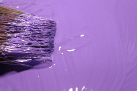 Paint brush with purple paint on a purple background close-upの写真素材