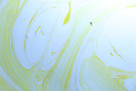 abstract background. Closeup of a mixing of yellow and white paints