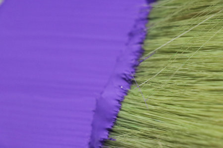 Paint brushes of different colors on a purple background close-upの写真素材
