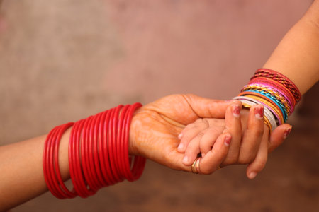 Close up of woman's hands holding her mother's hand with red ropeの写真素材