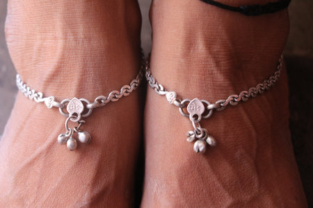 A pair of women's legs with silver bracelets and beads.