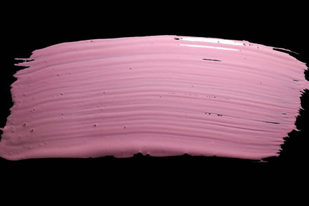Pink paint brush stroke isolated on black background. Texture of cosmetic productの写真素材