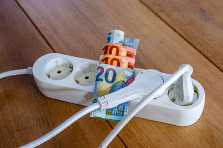 Powerstrip with plugs and Euro banknotes to illustrate the rise of the electricity and daily life expensesの写真素材