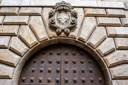 Facade of an old building with a coat of arms with a cross in the Gothic Quarter of Barcelona, Catalonia, Spain, Europeの写真素材