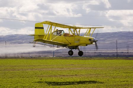 Aircraft-Crop duster spraying fields with chemical insecticides to prevent spoilageの写真素材
