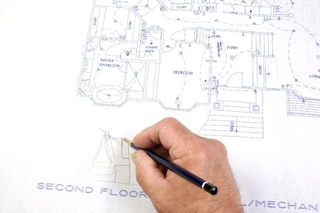 Contractor making changes to a set of building plans for a custom house with draughting tools