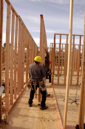 Hispanic carpenters setting a wall at a House under construction