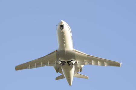 Modern private jet aircraft flying overhead after takeoff with undercarraige retracting