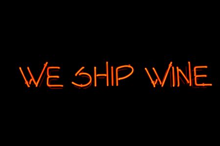 Orange Neon sign - over black stating "We ship wine"の写真素材