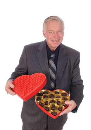 Sweets for my sweet, man in business suit offering chocolates and flowers to his sweetheartの写真素材