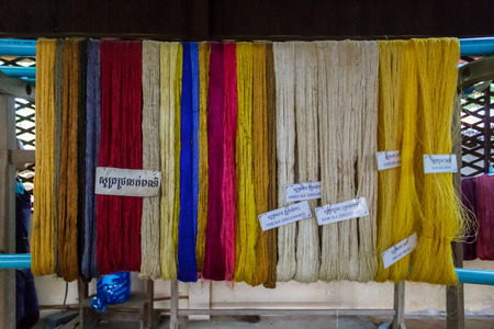 SIEM REAP, CAMBODIA - AUGUST 24, 2015: Yellow, white, blue, and red silks hanging up after being dyed.のeditorial素材