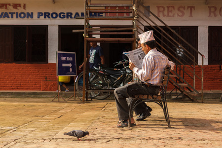 KATHMANDU, NEPAL - 9/26/2015: A Nepalese man reads a newspaper on a bench near Durbar Square in Kathmandu, Nepal.のeditorial素材
