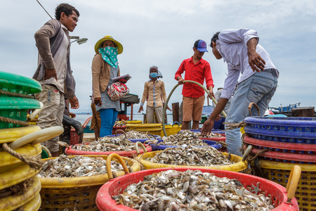 SIHANOUKVILLE, CAMBODIA - 7/20/2015: A group of workers help fishermen prepare on the docks of a fishing village.のeditorial素材