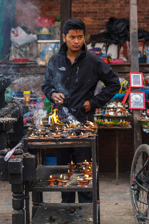 KATHMANDU, NEPAL - 9/26/2015: A candle salesman smokes a cigarette at Durbar Square during the Indra Jatra festival in Kathmandu, Nepal.のeditorial素材