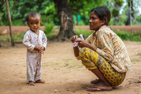 SIEM REAP, CAMBODIA - 9/12/2015: A mother crouches next to her boy in a village.のeditorial素材