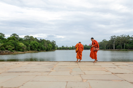 SIEM REAP, CAMBODIA - 6/26/2015: Two monks walk across the sandstone causeway towards the west gate of Angkor Wat.のeditorial素材