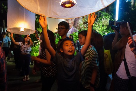 CHIANG MAI, THAILAND - 12/30/2015: A young boy releases a floating lantern at a temple on New Year's Eve in Chiang Mai, Thailand.のeditorial素材